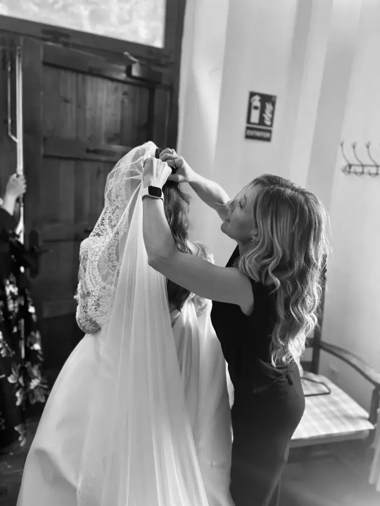 Laura colocando el velo a una novia, en blanco y negro